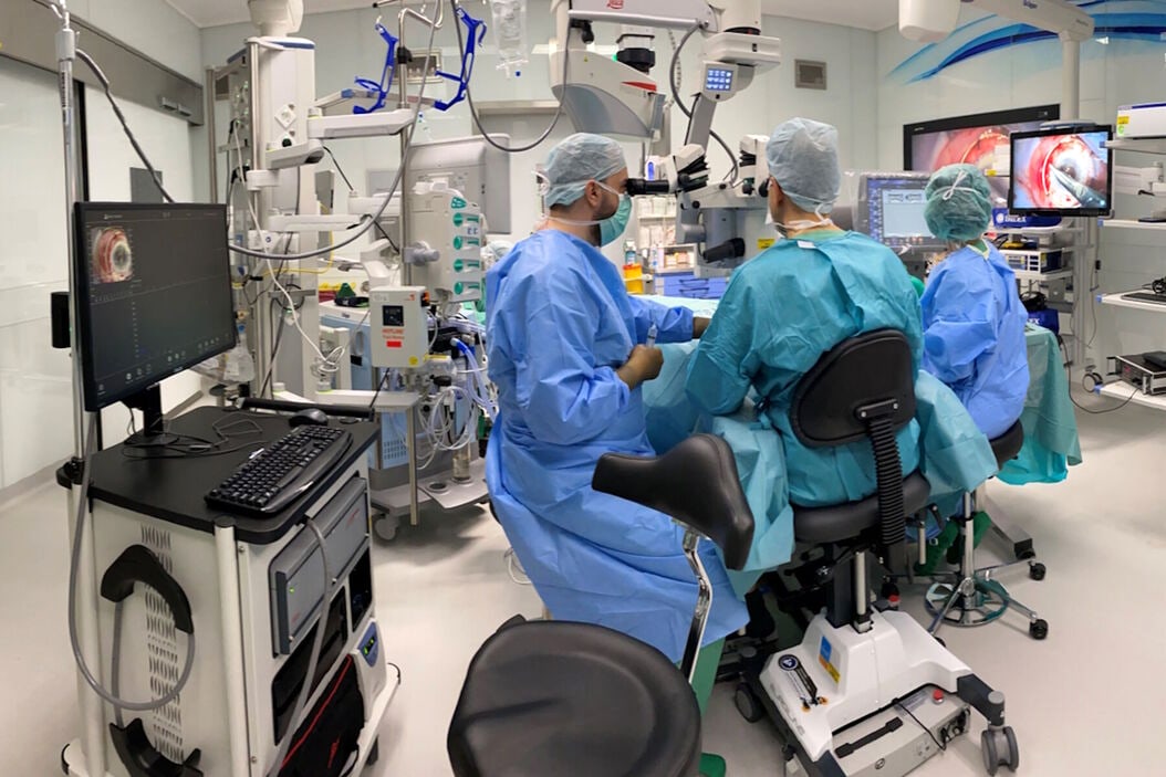 A surgical team working together at an operating microscope.