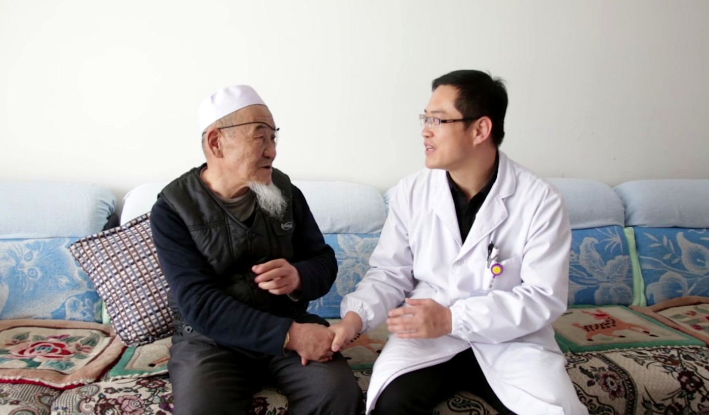 Local doctor speaking with an older patient during a home follow-up visit