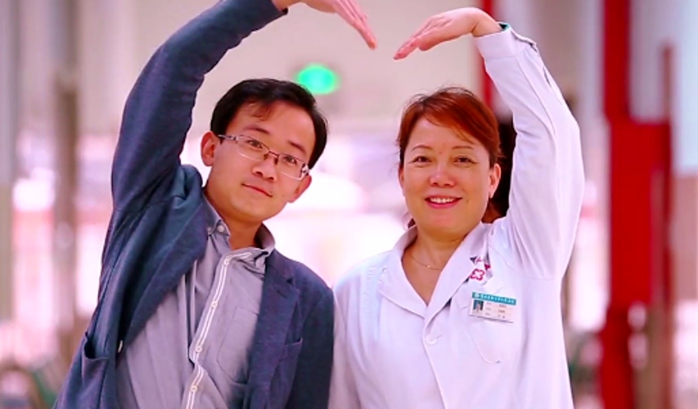 Two project participants making a heart gesture in a hospital corridor